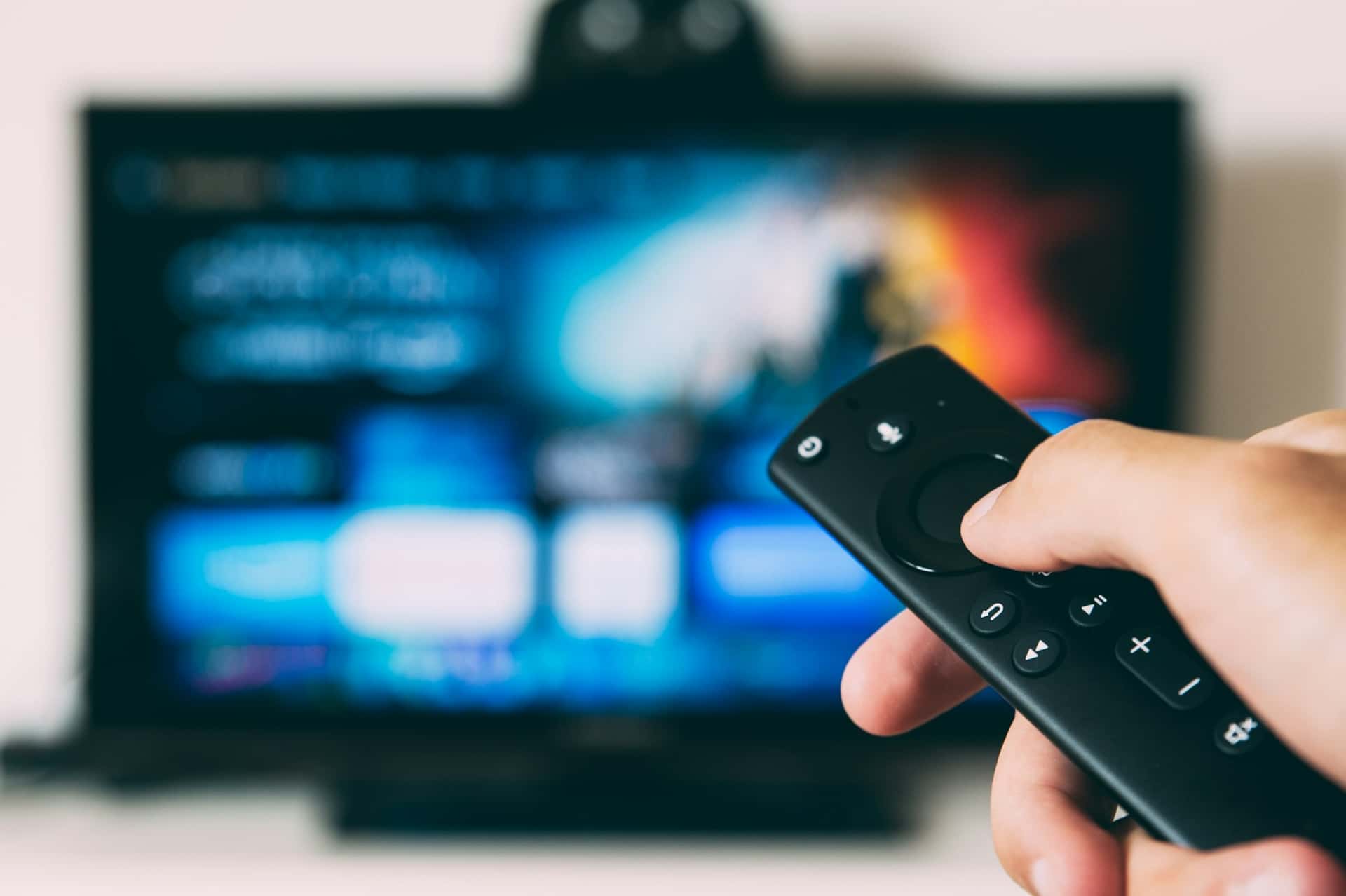 Hand met afstandsbediening gericht op een televisie